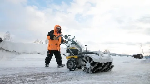 Man cleans snow in the yard with a sweeper in the winter Stock Footage 125825521