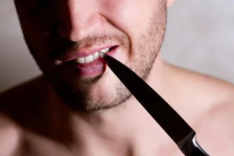 Man cleans the space between his teeth with a knife, close up Stock Photos