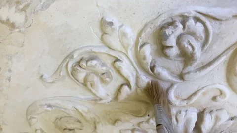 A man cleans the stucco molding on the ceiling with a brush. Restoration of old Video stock 170894868
