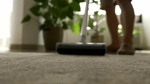 A man cleans the surface of a carpet with a cordless vacuum cleaner. 스톡 동영상 202010288