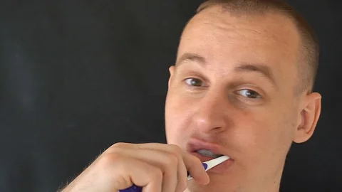 Man Cleans Teeth on black background Stock Footage 76631175