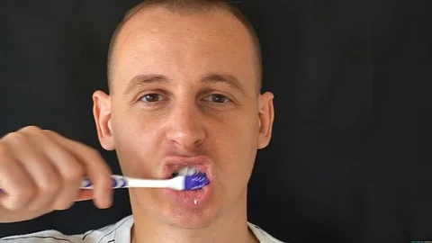 Man Cleans Teeth on black background Stock Footage