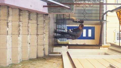 A man cleans the tile on the sidewalk from the build up of dirt. vertically Stock-Footage 128075707