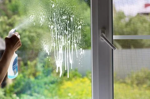 Man cleans a window detergent Stock Photos