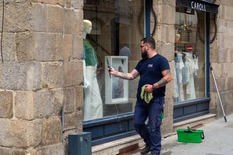 A man cleans a window with spray and a rag. Rennes 08 June 2026 Stock Photos