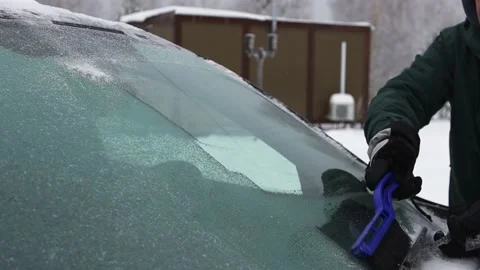 A man cleans the windshield of a car from snow with a brush Stock Footage 167307254