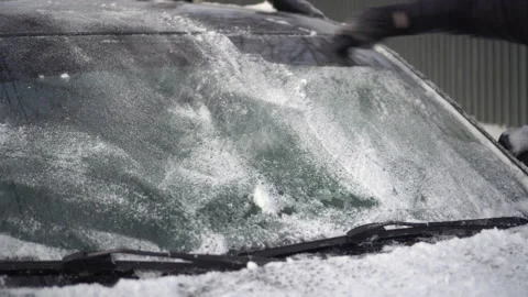 A man cleans the windshield of his car from ice with a scraper close-up. The car Stock Footage 168544041
