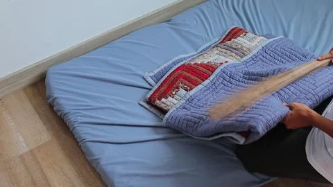 Man clearing and sweeping floor bed mattress after removing quilt in room 库存影片 341994676