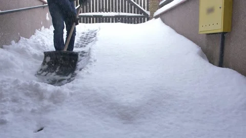 Man Clearing Backyard Pavement of Snow with Snowshovel Stock Footage 147084576