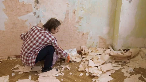 Man clearing construction waste and old wallpaper into a trash bag, preparing Stock Footage 329757458