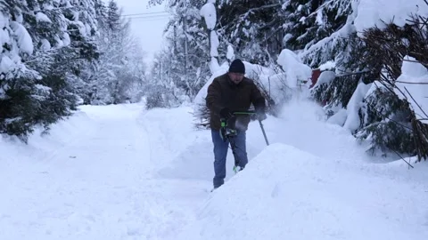 Man clearing deep snow with a snow blower on a winter residential road surrounde Video stock 326160955