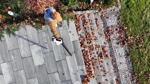 Man Clearing Leaves From Patio During Autumn Season in Yard Using Air Blower Stock Footage 301976003