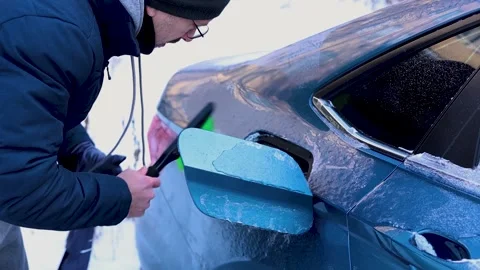 A man clears ice from his car. Stock Footage 327302940