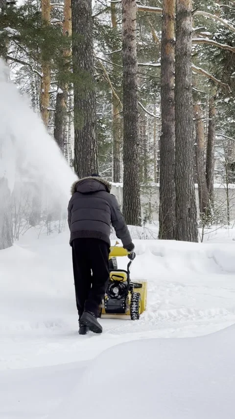 A man clears snow with a snow blower in his yard. Stock Footage 320357567