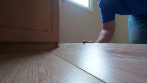 Man clicking white oak laminate flooring planks together during home renovation. 스톡 동영상 341076543