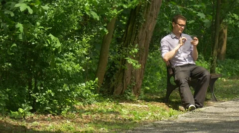 Man Clicks a Tablet Sitting on Bench in Park Chatting Forex Real Estate Stock Footage 63810619