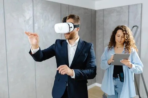 Man client wearing VR glasses imagining future interior standing with desig.. Stock Photos