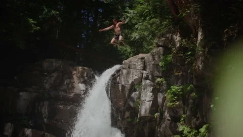 Man cliff jumps into waterfall pool in beautiful forest 库存影片 220301795