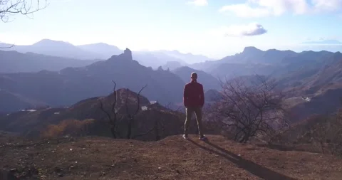 Man on Cliff looking out at Beautiful Mountain Chain to the Horizon Vídeo Stock 135902887