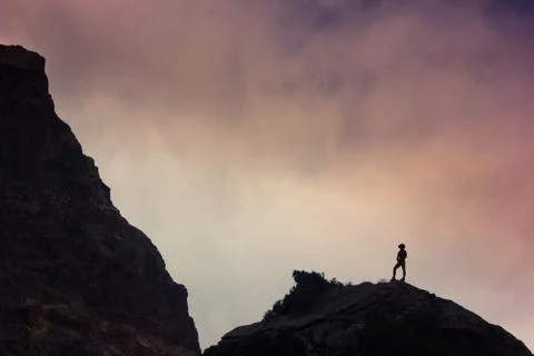 Man on a cliff in mountains Stock Photos