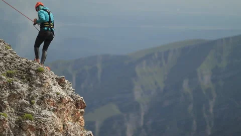 Man climber gently descends to the edge of the cliff. Stock Footage 97713066