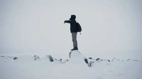 Man climbing with backpack looking around. Snow weather highlands horizon. Stockbeeldmateriaal 102792812