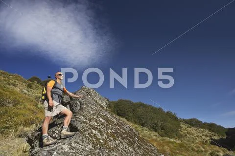 Man Climbing Up Boulder In Forest Valley Stock Photos