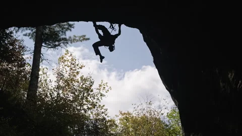 Man climbing a cliff in a cave Stock Footage 266813252
