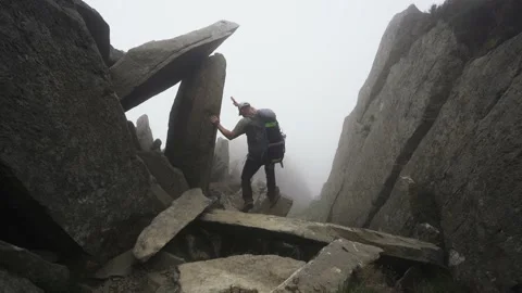 A man climbing down a misty perilous and dangerous rocky mountain Video stock 140753927