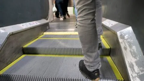 Man climbing the mechanical stair with gray pants Stock Photos