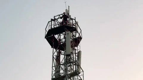 Man Climbing Mobile Tower in Rural Area Highlighting Dangerous Risk Stock Footage 323103891