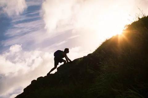 Man climbing up a mountain. Self improvement and life goals concept. Stock Photos