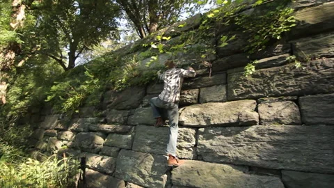 Man climbing over stone wall in Riverside Park, New York City, New York, United Vidéo 194101349