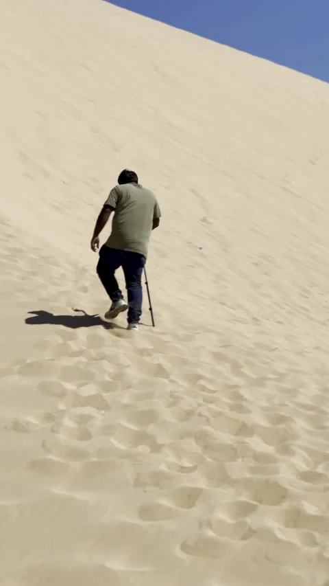 Man Climbing Steep Sand Dune in Desert Heat Vídeo Stock 325661965