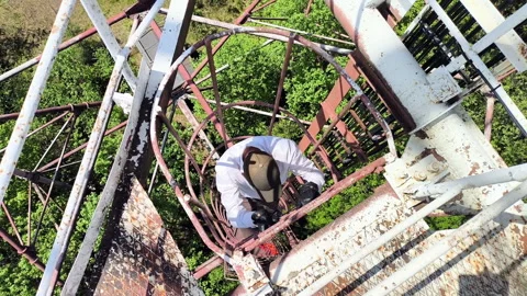 Man climbing vertical cage ladder inside 75m repurposed radar tower Video stock 337952527