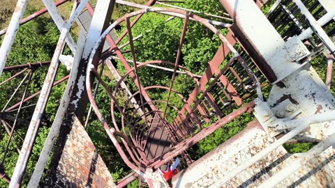 Man climbing vertical cage ladder inside 75m repurposed radar tower Stock Footage 337952534