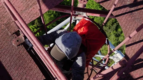 Man climbing vertical cage ladder inside 75m repurposed radar tower Video stock 337953326