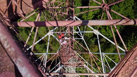 Man climbing vertical cage ladder inside 75m repurposed radar tower Stock Footage 337953451