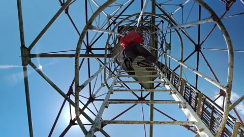 Man climbing vertical cage ladder inside 75m repurposed radar tower Stock Footage 338115393