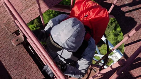 Man climbing vertical cage ladder inside 75m repurposed radar tower Video stock 338115685