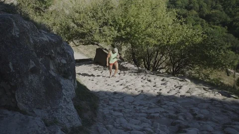 A man climbs the ancient stone pavement in the cave town. Crimea, Chufut Kale. Stock Footage 94848713