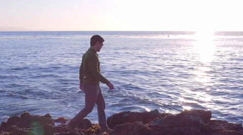 Man Climbs Around On Rocks, Exploring The Beach At Sunset Stock Footage 47293799