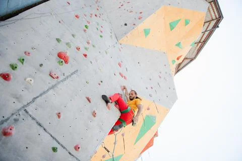 A man climbs up an artificial wall at a climbing wall. Stock Photos