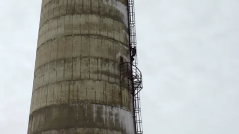 A man climbs a high abandoned pipe to make a parachute jump Stock Footage 195557909