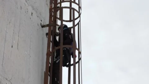 A man climbs a high abandoned pipe to make a parachute jump. Stock Footage 195557912