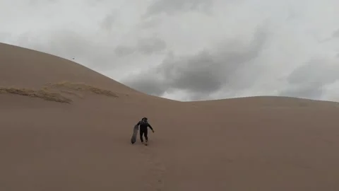 Man Climbs Up Large Dune with Sand Board, Great Sand Dunes, Colorado Stock Footage 146554007