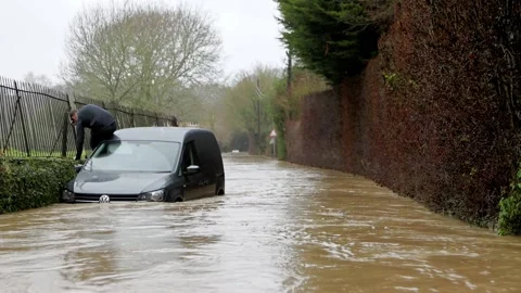 Man climbs out of his broken down van on a flooded country lane. UK Stock Footage