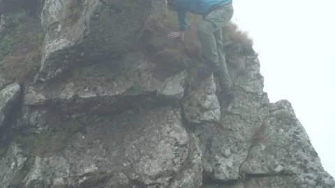 A man climbs the rocks on the mountain. A dangerous adventure Stock Footage 218441897