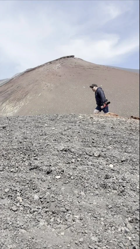 A man climbs the rugged slopes of Mount Etna volcanic terrain Stock Footage 311096582