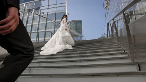 Man Climbs The Stairs Up. On The Upper Steps Charming Bride In White Dress. Stock Footage 153746498